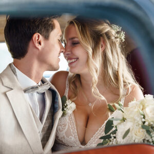 Brautpaar in einem Oldtimer mit der Nase sich küssend